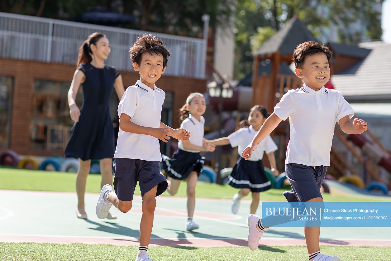 Chinese teacher and students playing in kindergarten playground
