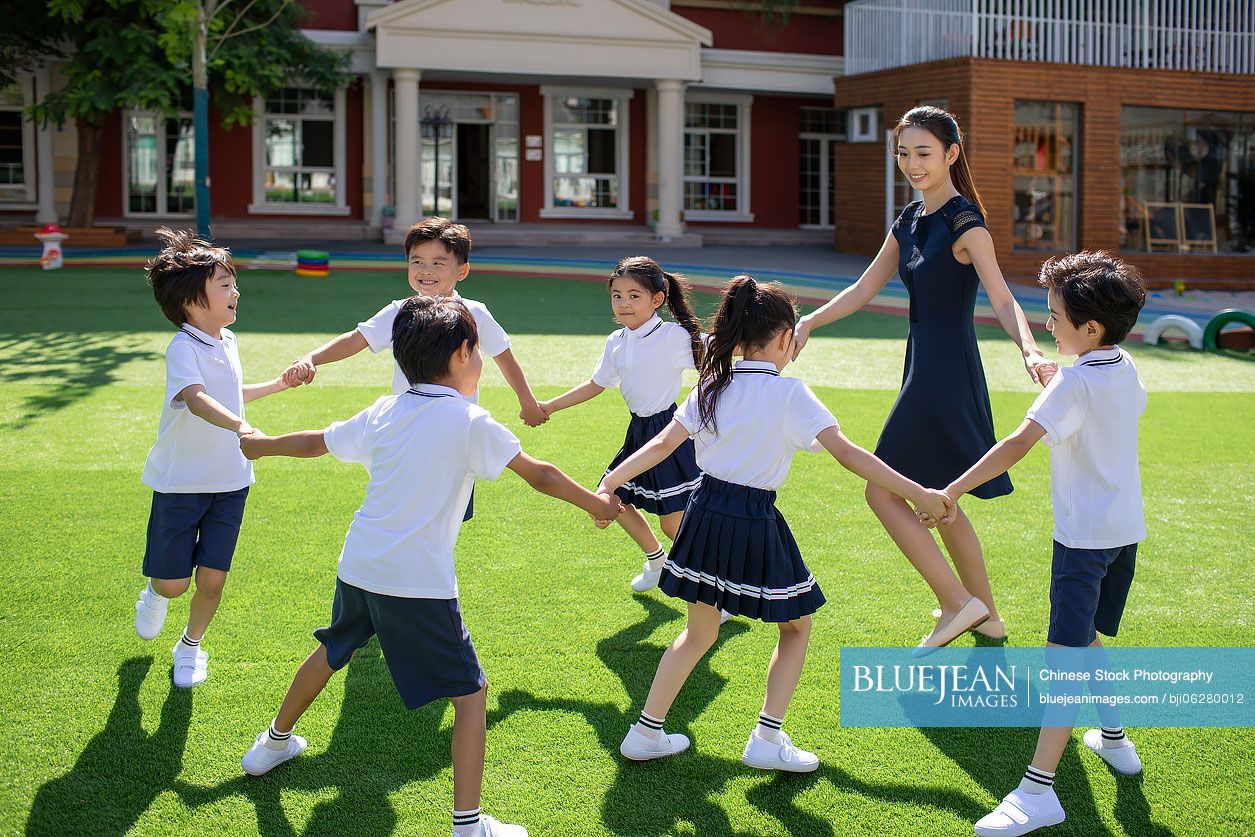 Chinese teacher and students playing in kindergarten playground