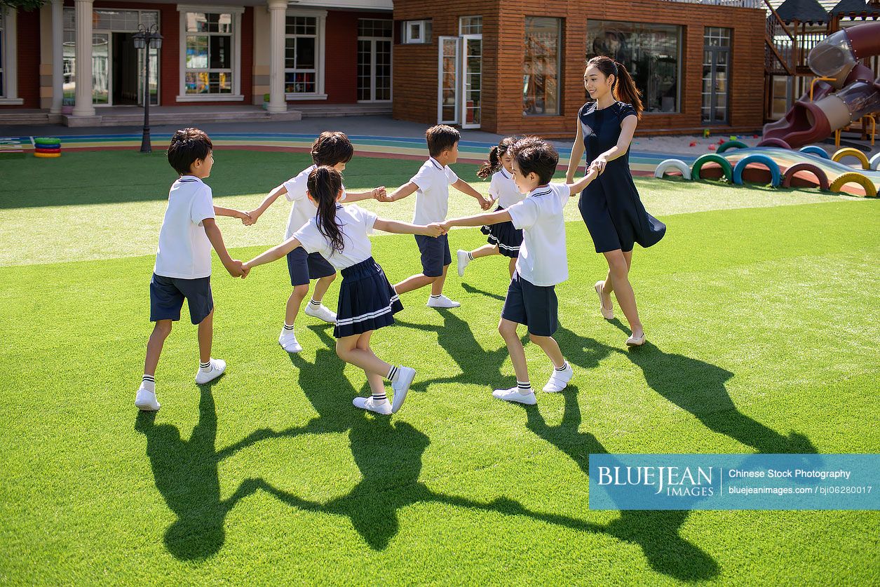 Chinese teacher and students playing in kindergarten playground