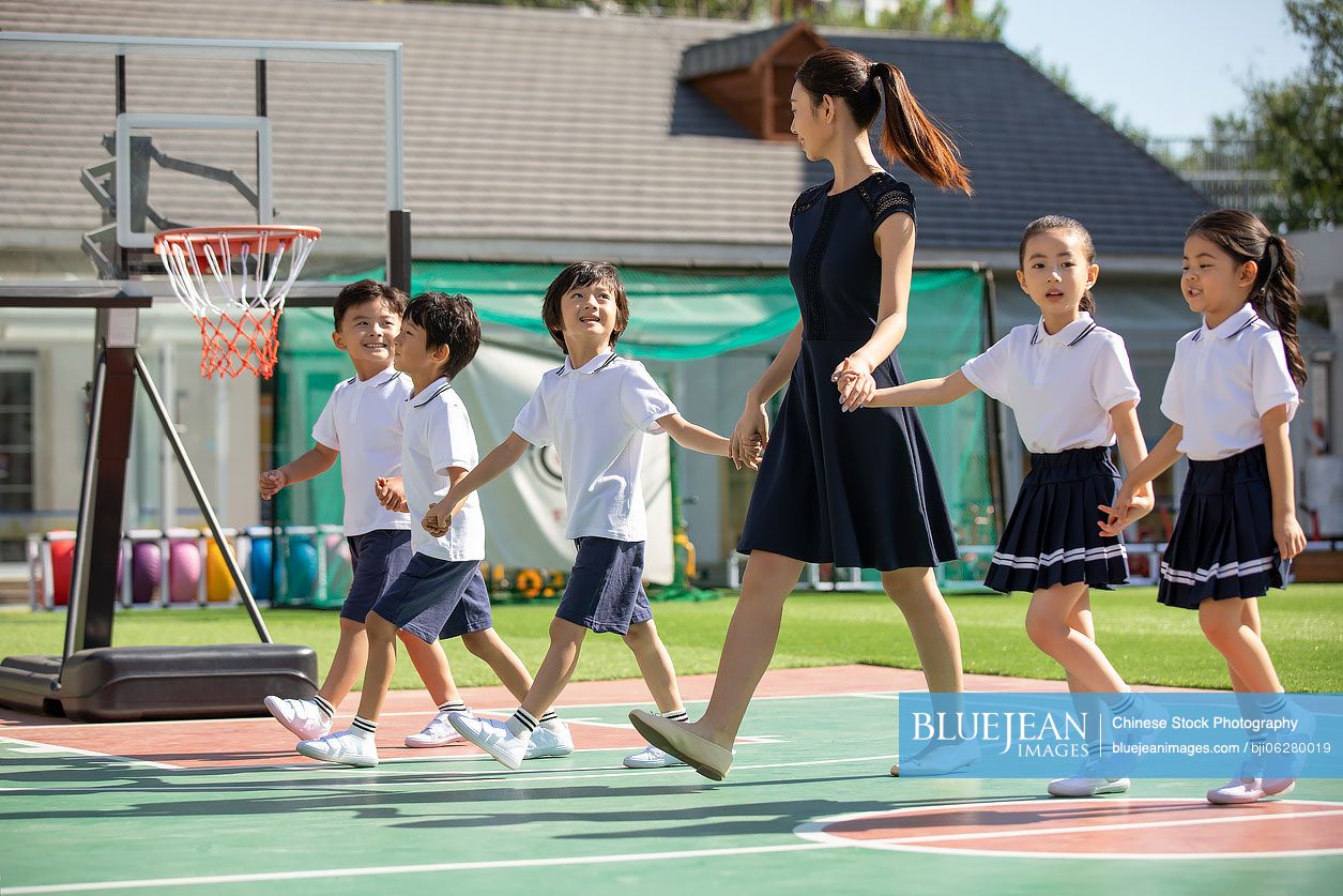 Chinese teacher and students in kindergarten playground