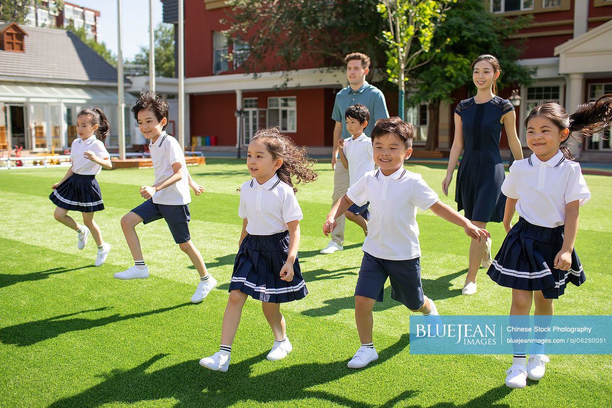 Teachers and children playing in kindergarten playground