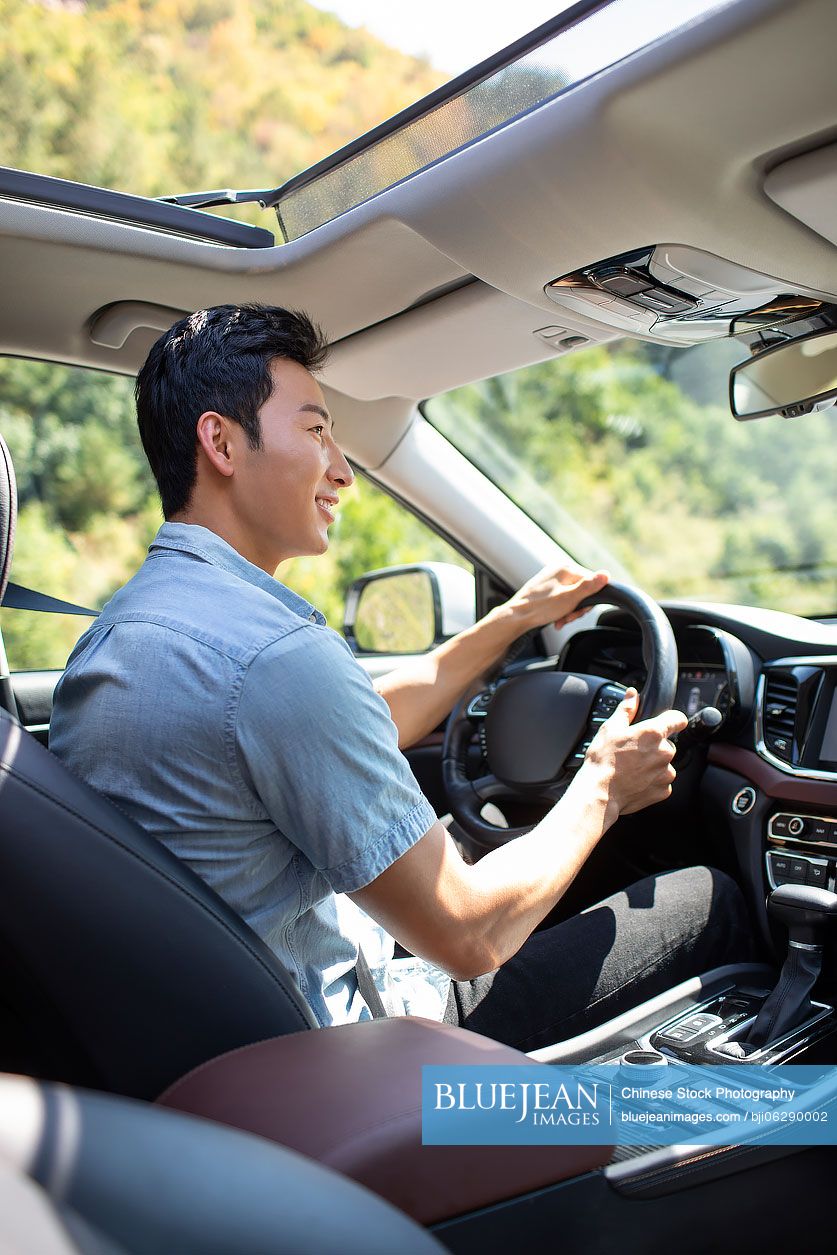 Happy young Chinese man enjoying road trip