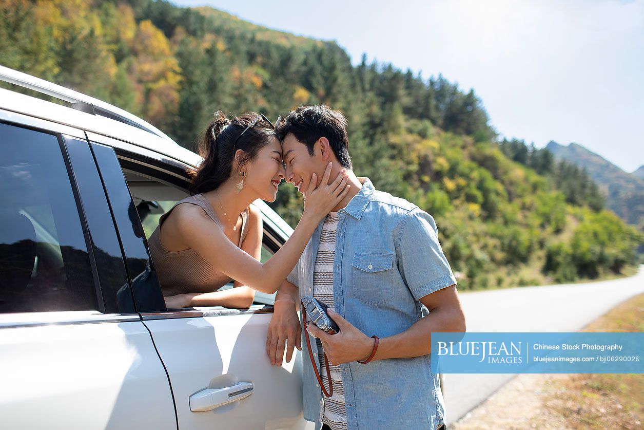 Happy young Chinese couple enjoying road trip