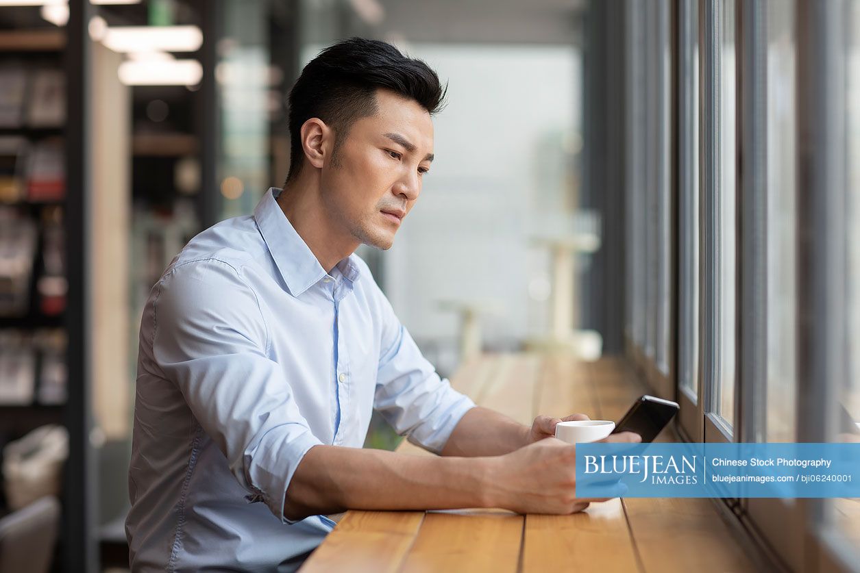 Chinese businessman using smart phone in café