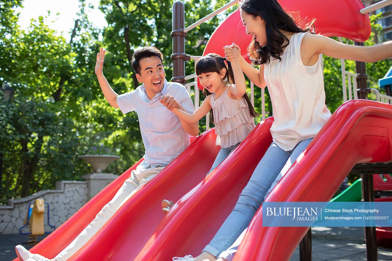 Happy young Chinese family playing in amusement park