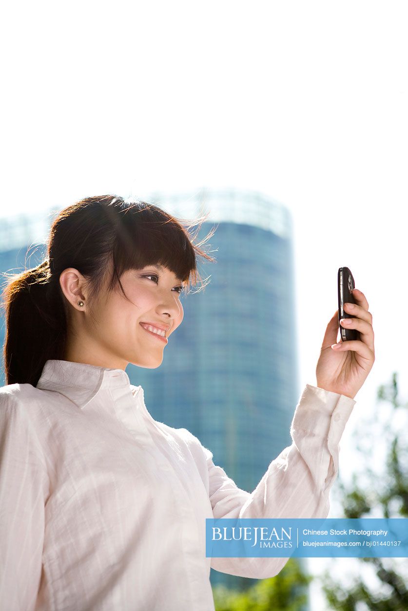 Chinese businesswoman on phone in front of skyscraper