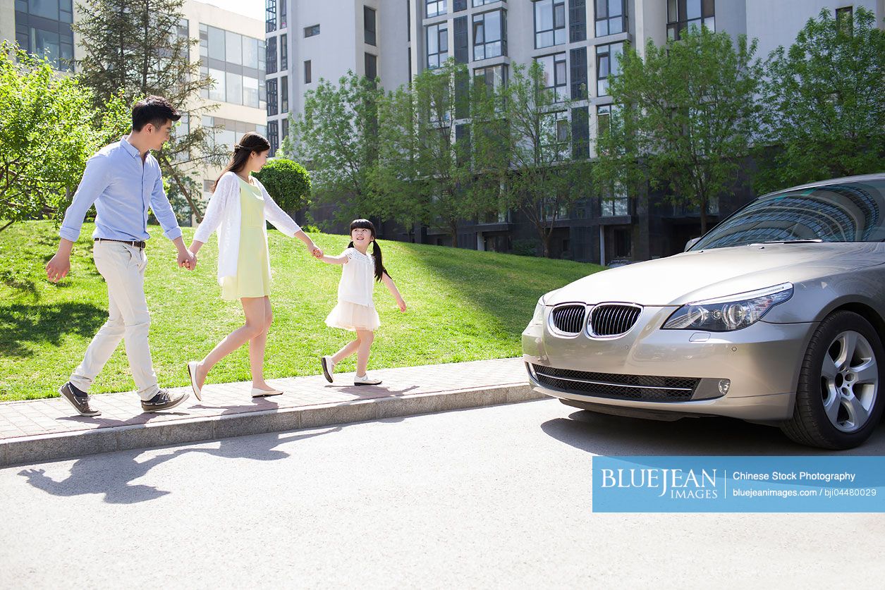 Happy young Chinese family holding hands walking