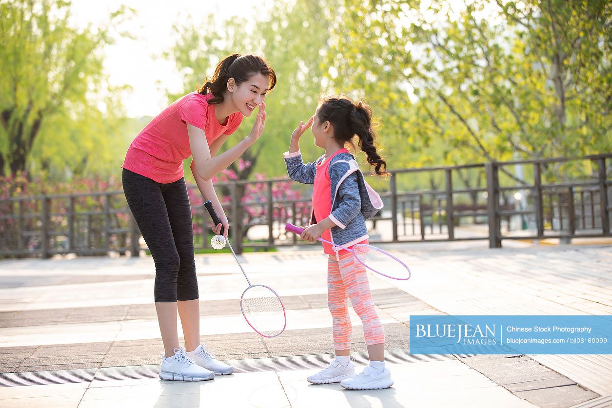 Happy Chinese mother and daughter playing badminton