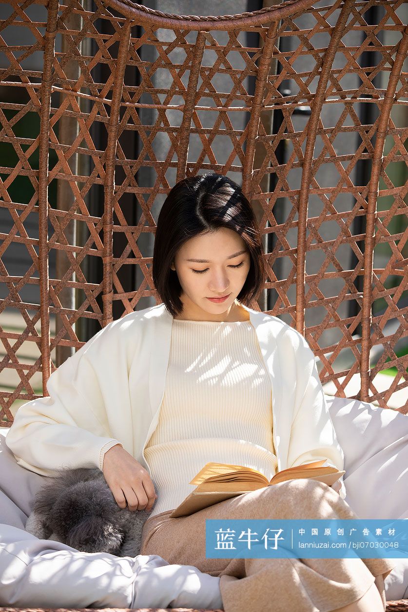 快乐的年轻女子在吊椅上看书