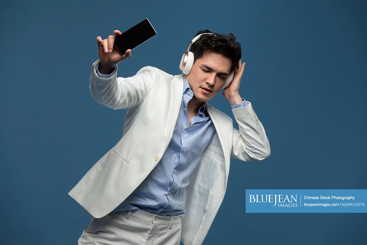 Studio shot of fashionable young Chinese man listening to music