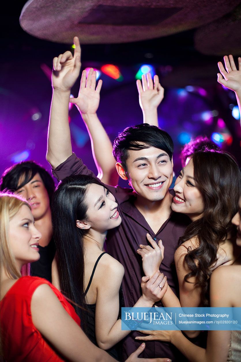 Young Chinese man surrounding by beautiful women in nightclub