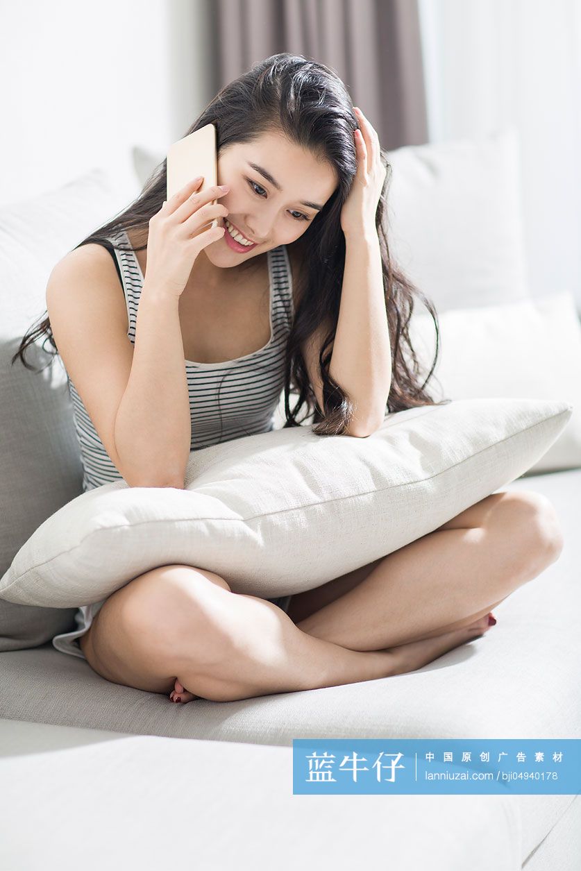 年轻女子坐在沙发上打电话