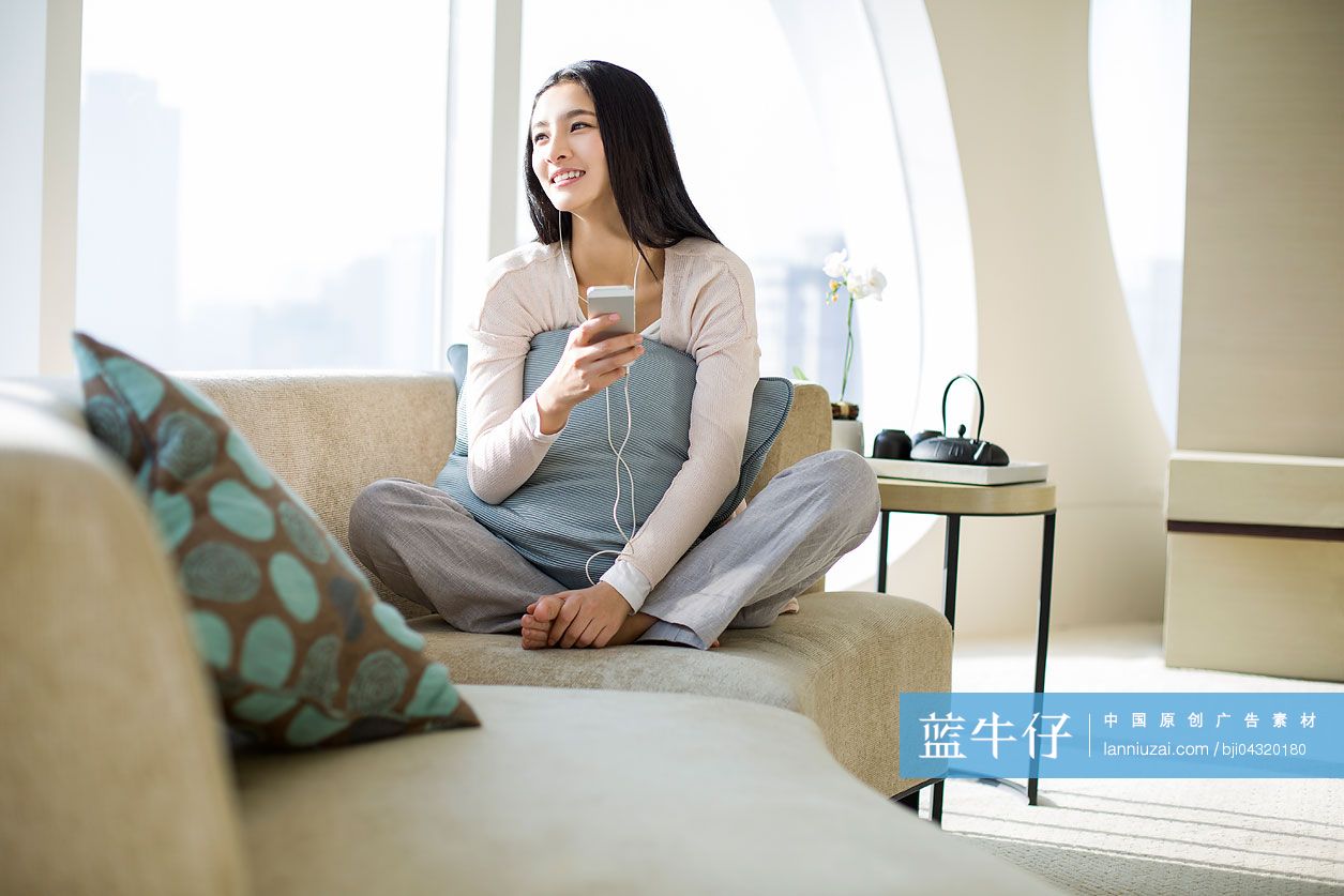 年轻女子在沙发上听音乐