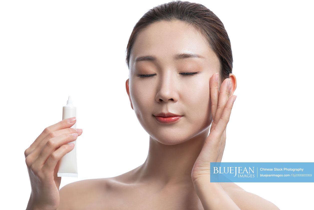 Beautiful young Chinese woman applying moisturizer