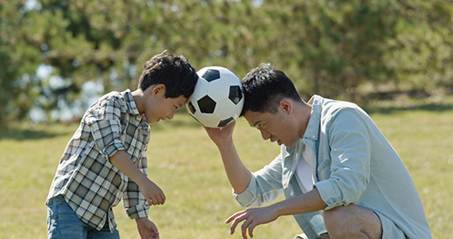 Happy Chinese father and son playing football in park,4K