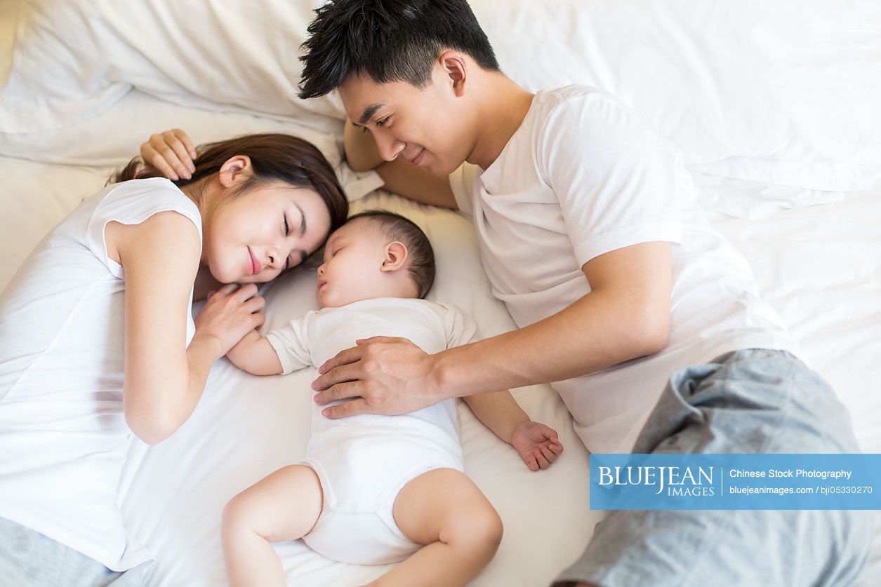 Young Chinese parents with sleeping baby boy