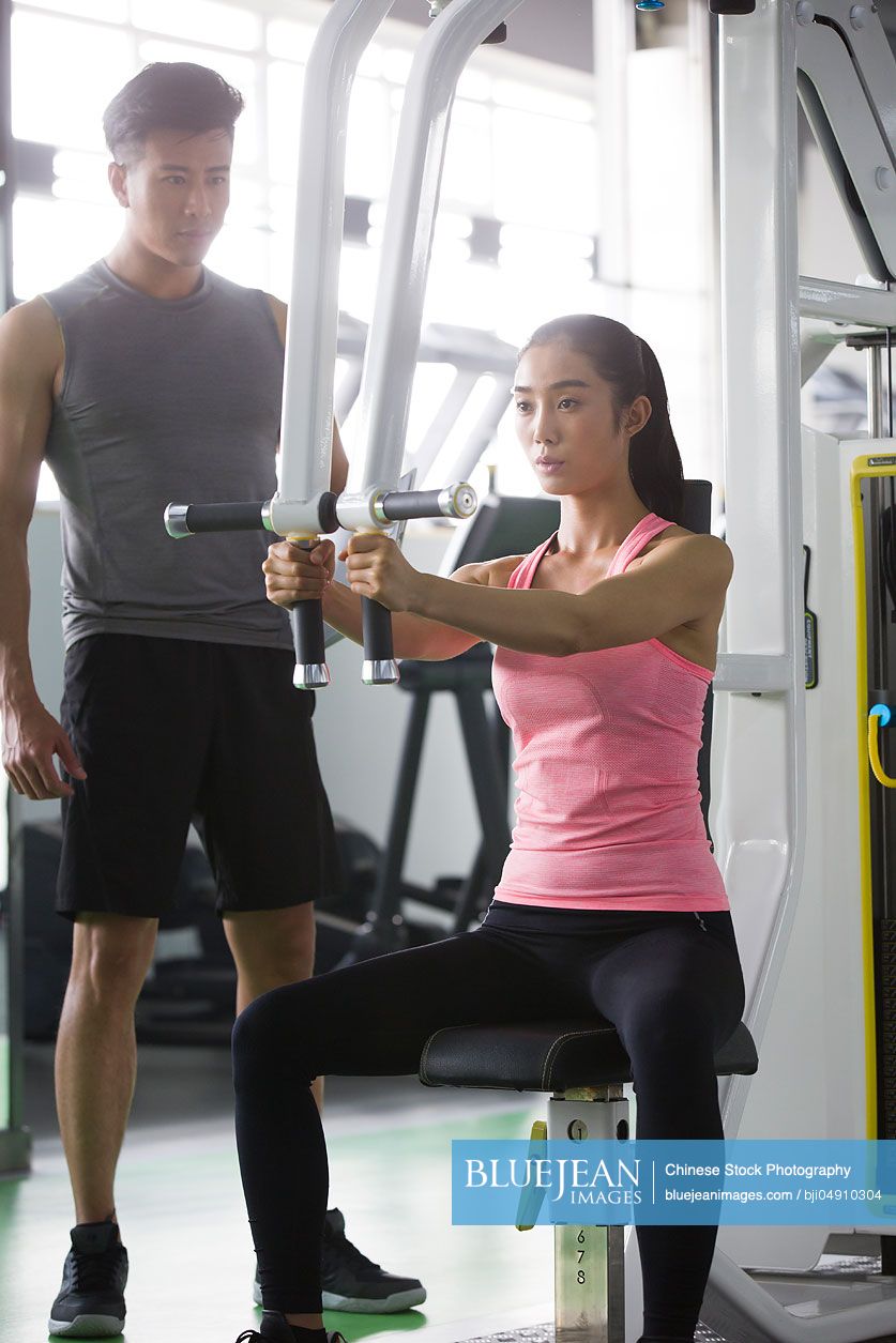 Young Chinese woman working with trainer at gym