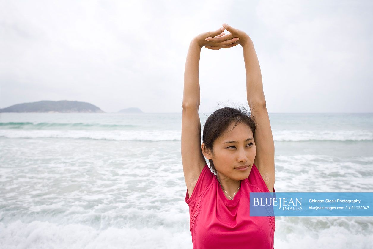 Young Chinese woman stretching by the sea