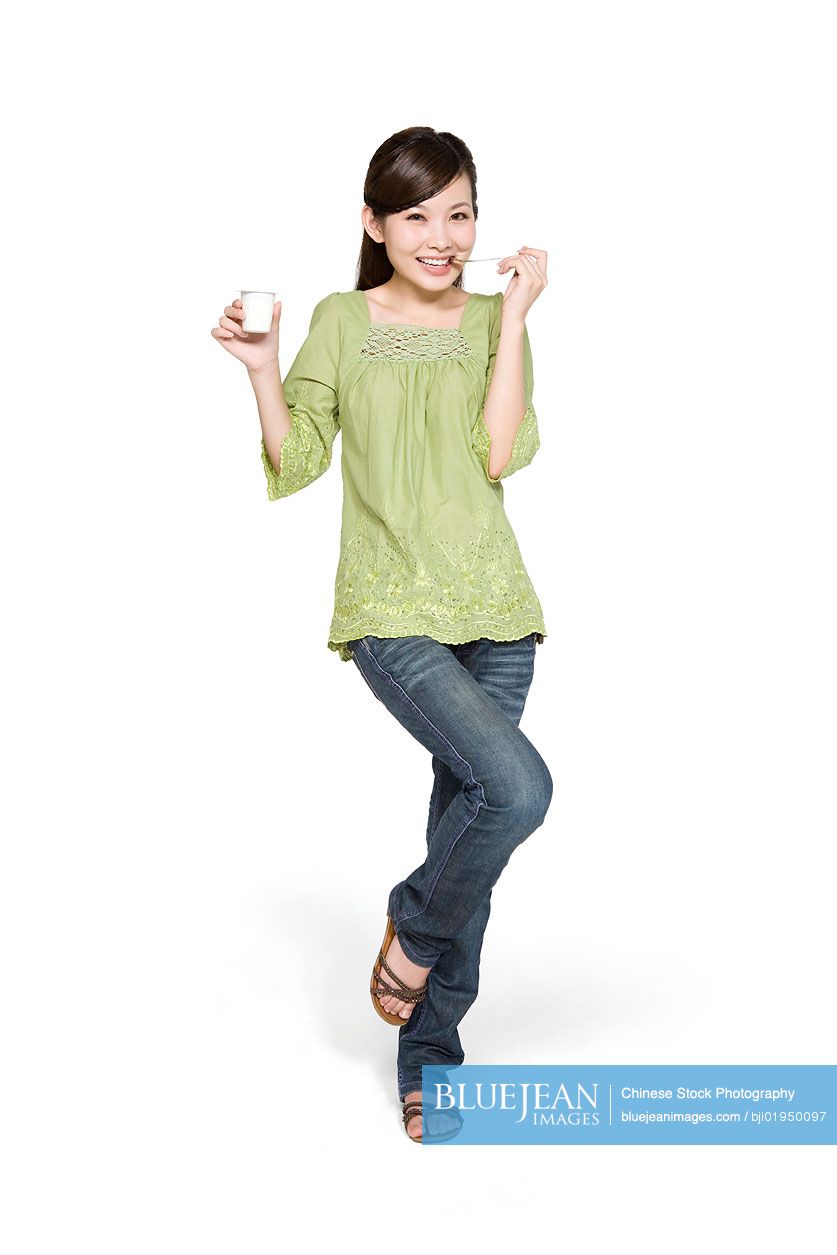 Portrait of young Chinese woman eating yogurt