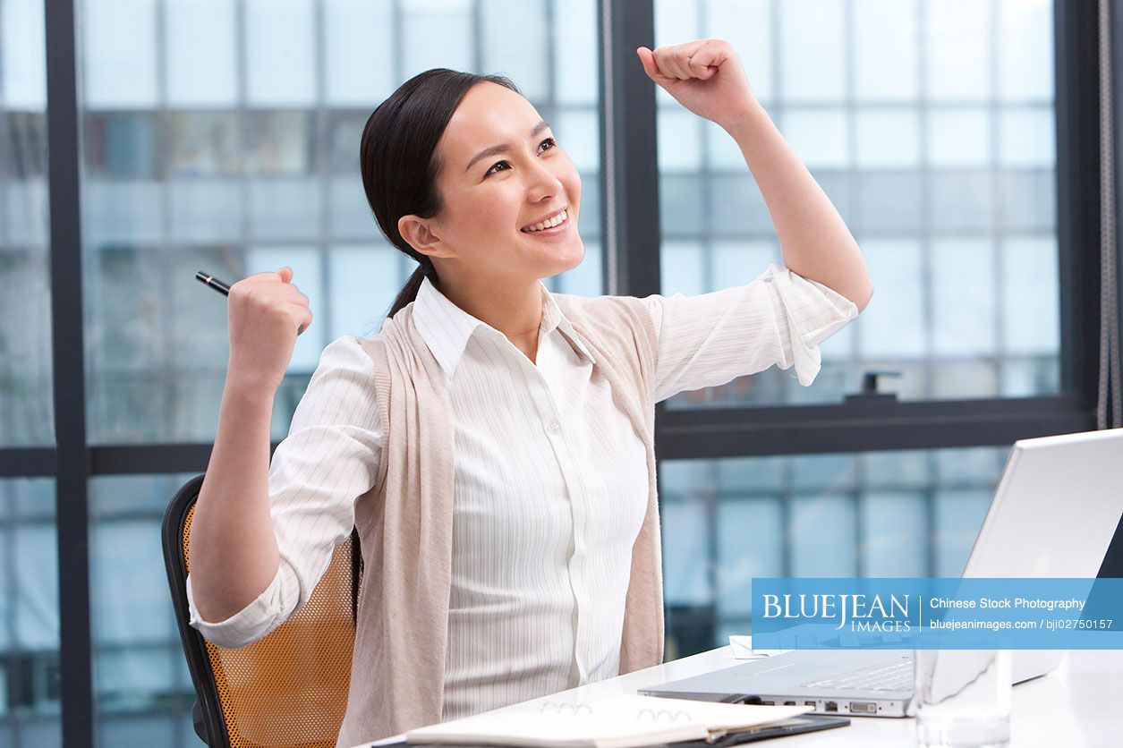 Chinese businesswoman with arms raised in celebration