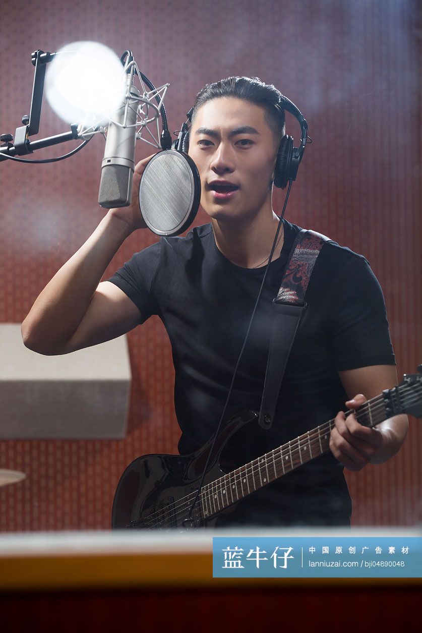 年轻男子在录音棚唱歌弹吉他