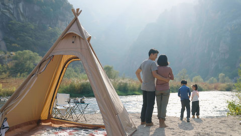 Happy young Chinese family camping outdoors