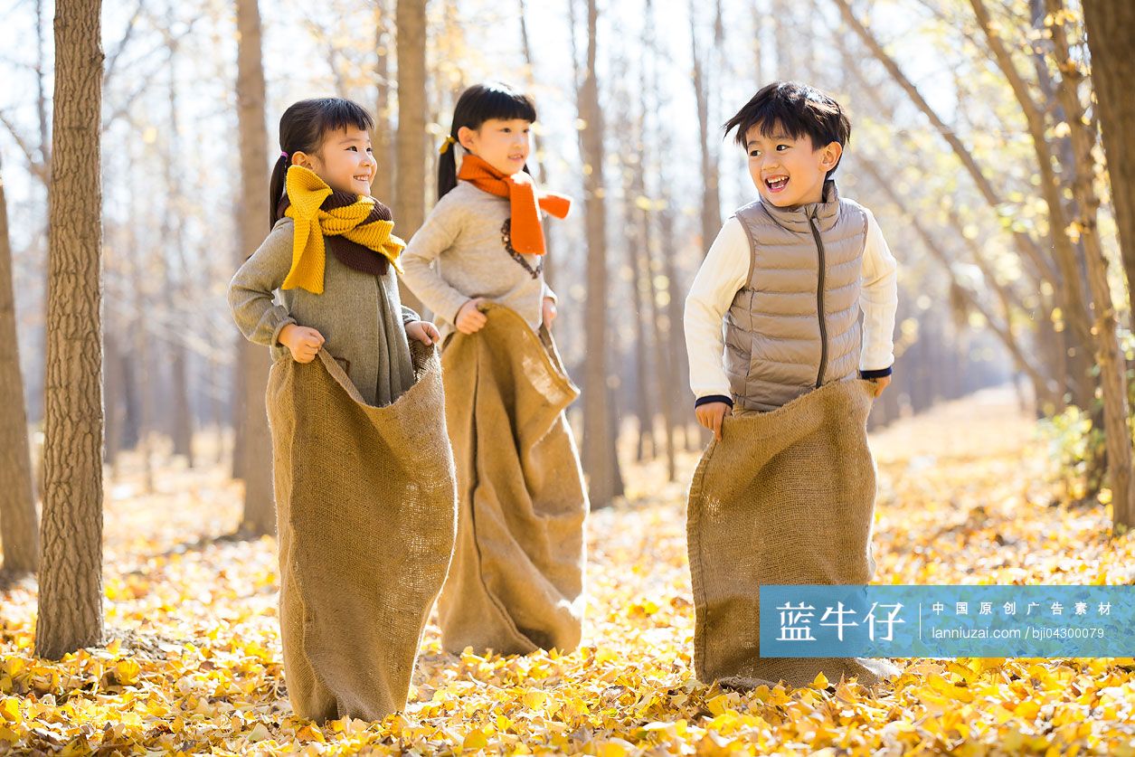 三个小孩在树林里玩布袋赛跑游戏