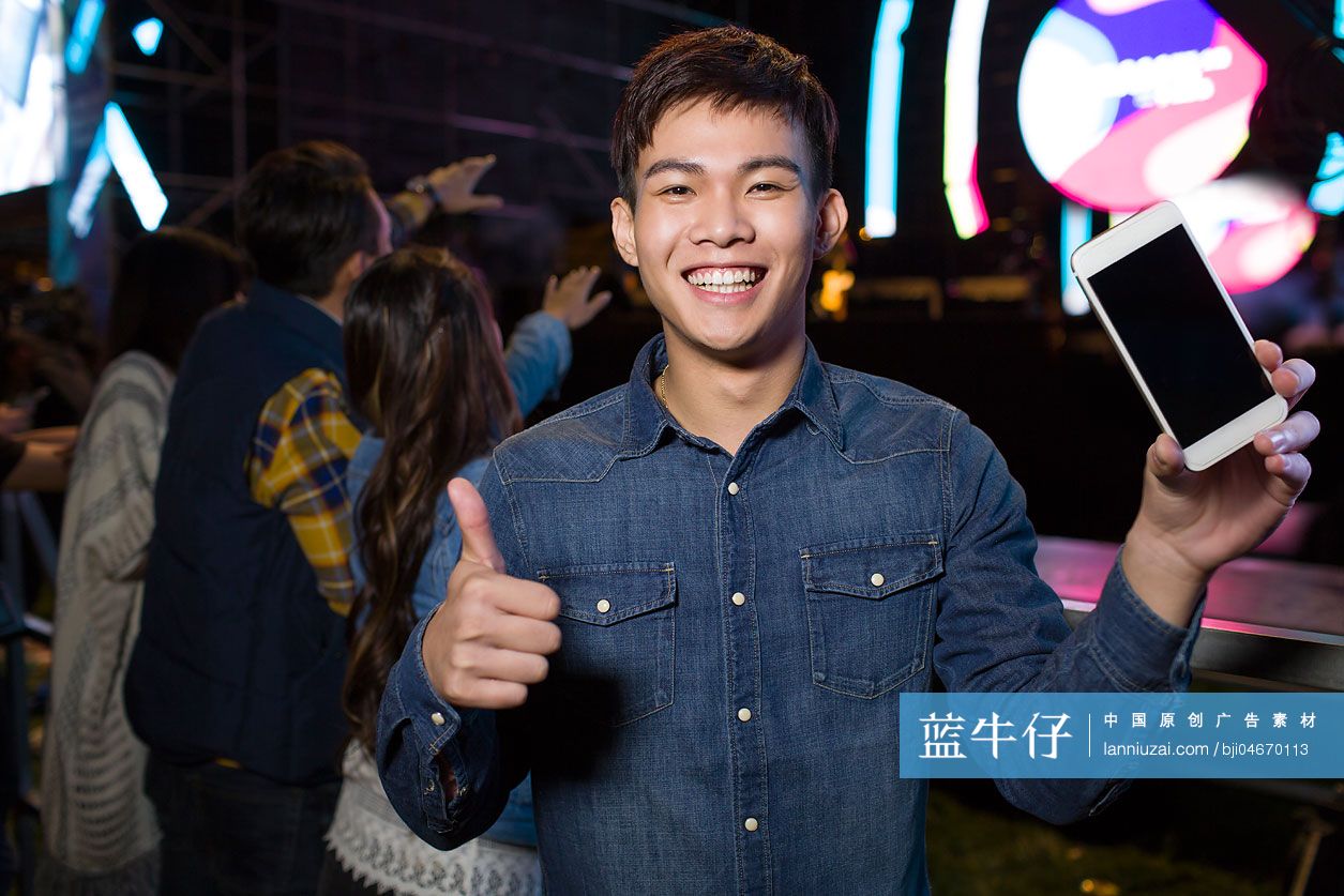 年轻男子在音乐节上展示手机
