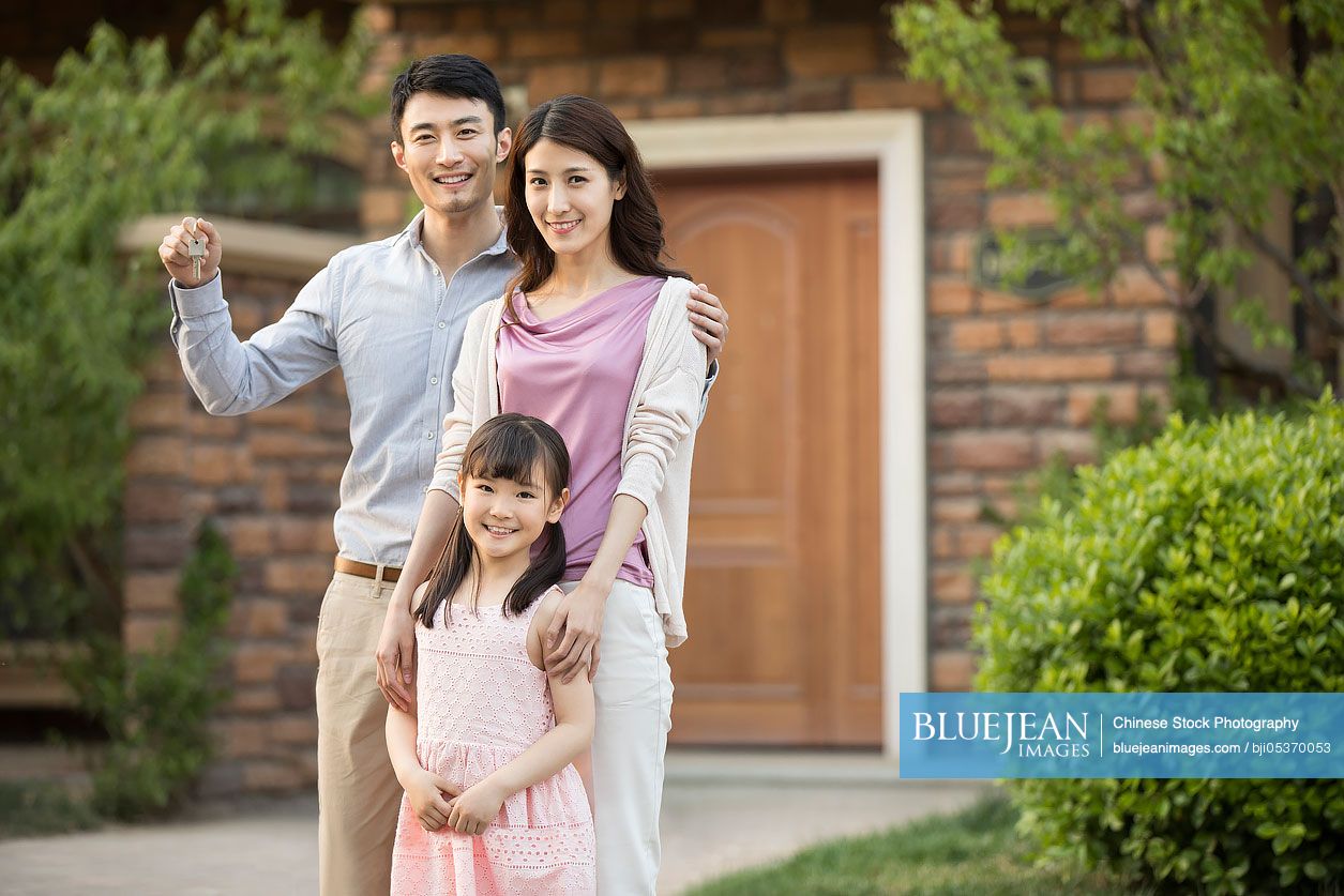 Happy young Chinese family holding keys to new house