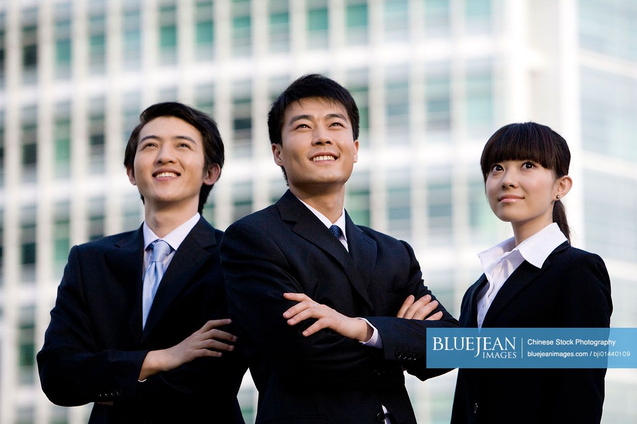 Three Chinese business professionals in front of skyscraper
