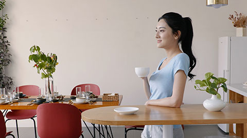 快乐的年轻女子在家喝咖啡