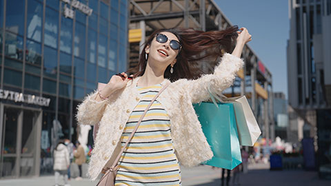 Cheerful young Chinese woman walking with shopping bags,4K