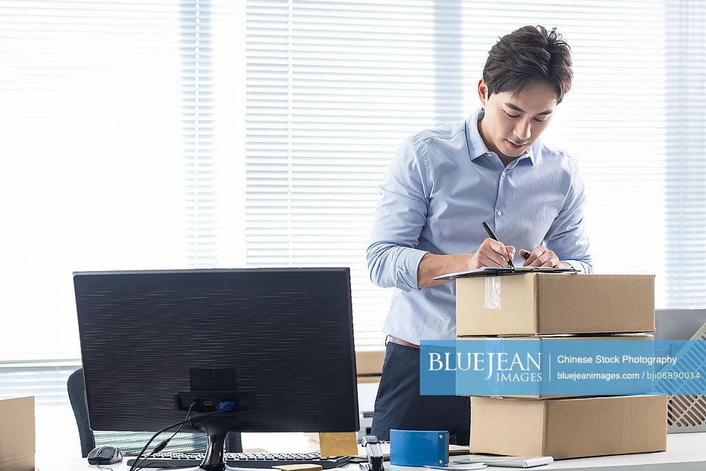 Chinese small business owner packing boxes in office