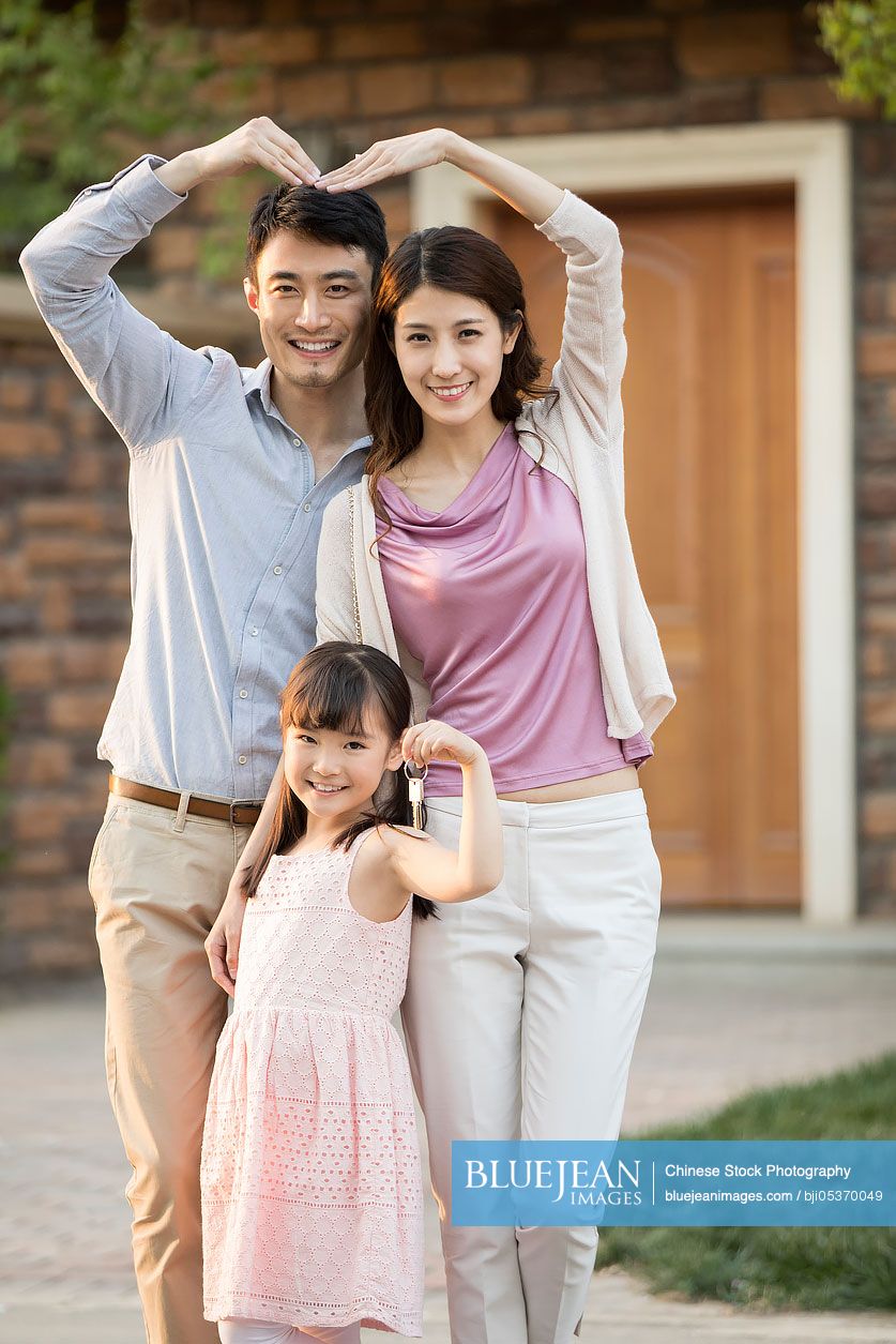 Happy young Chinese family holding keys to new house