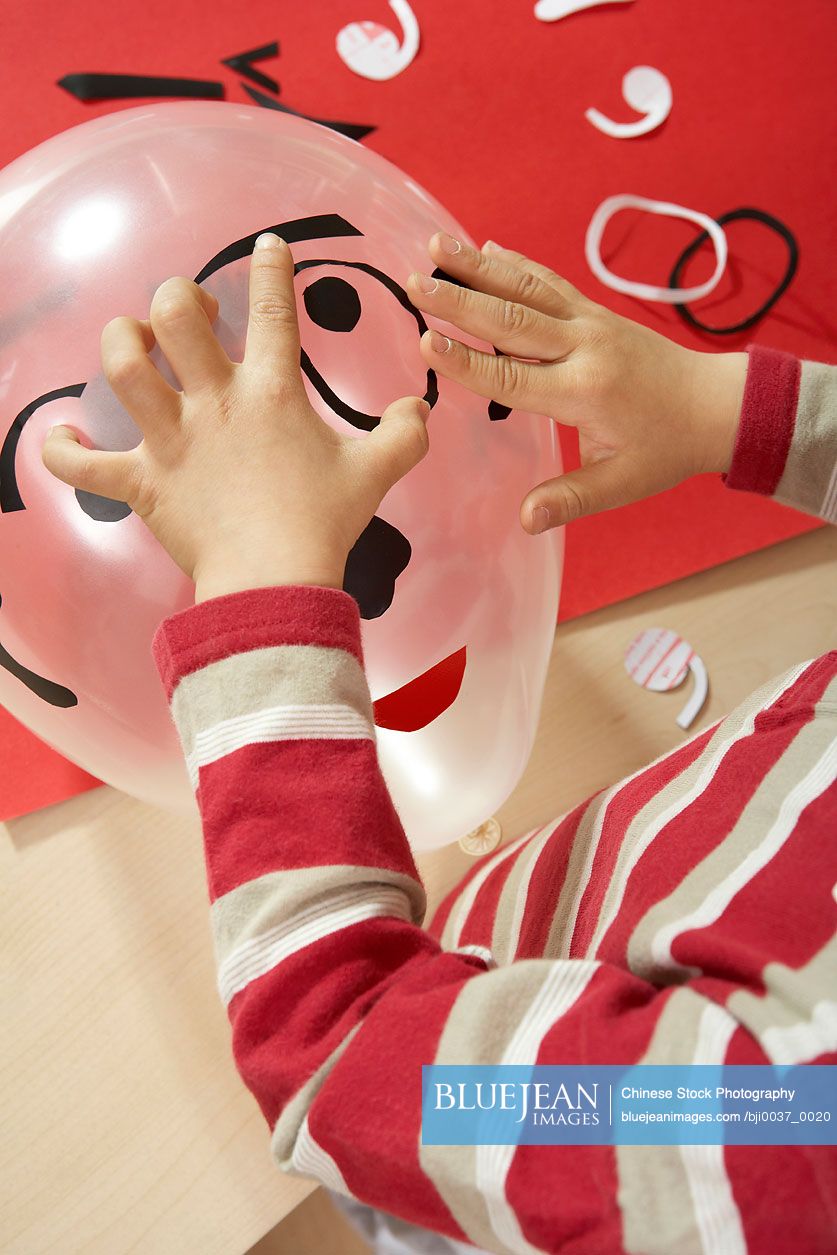 Chinese Child Decorating A Balloon Like A Face