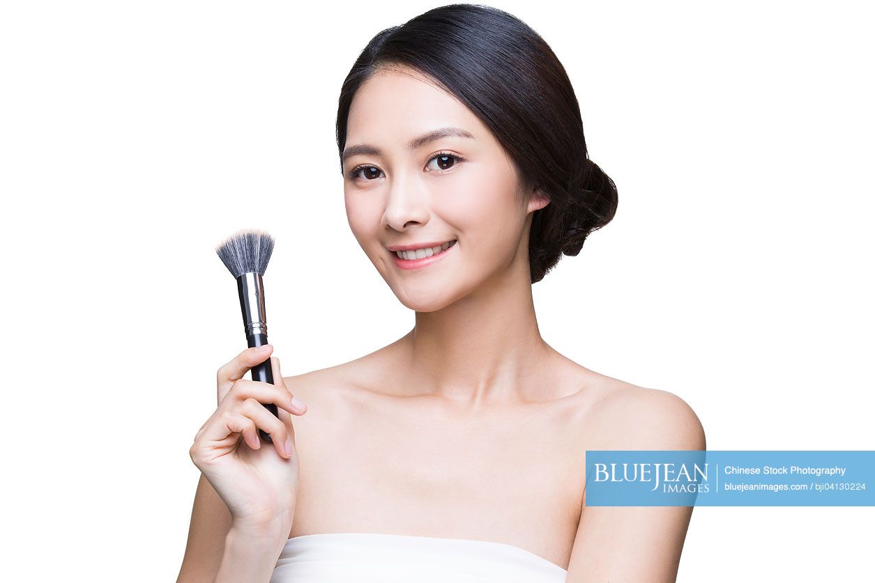 Beautiful young Chinese woman with cosmetic brush