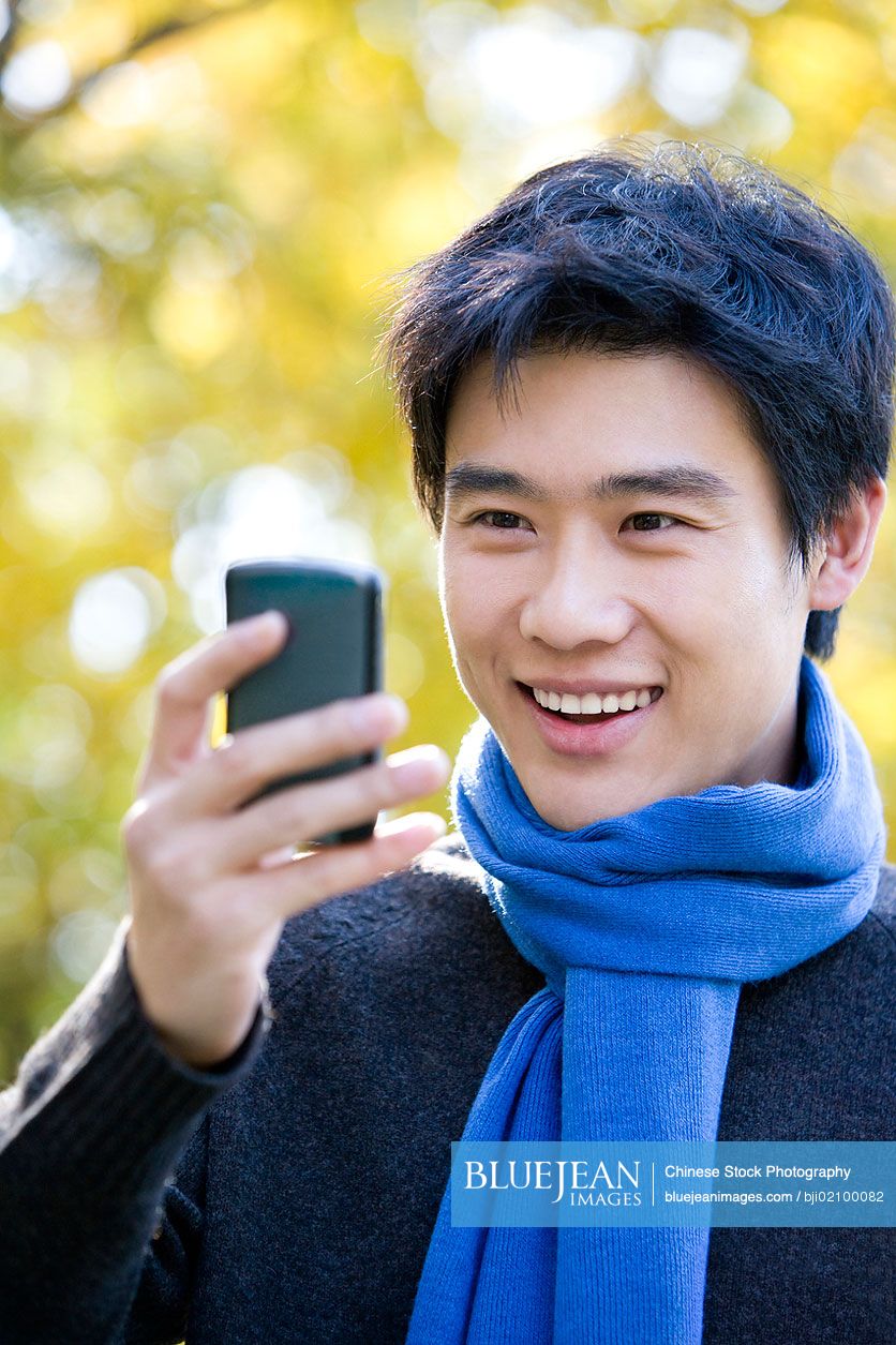 Young Chinese man texting on a smart phone