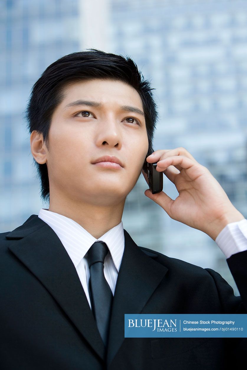 Young Chinese businessman using cellphone