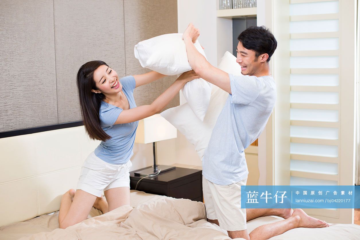 年轻夫妇在卧室打枕头仗