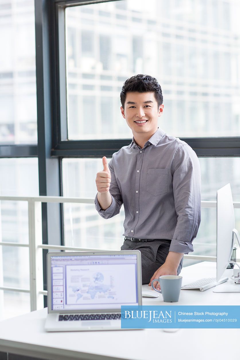Young Chinese businessman giving thumbs up