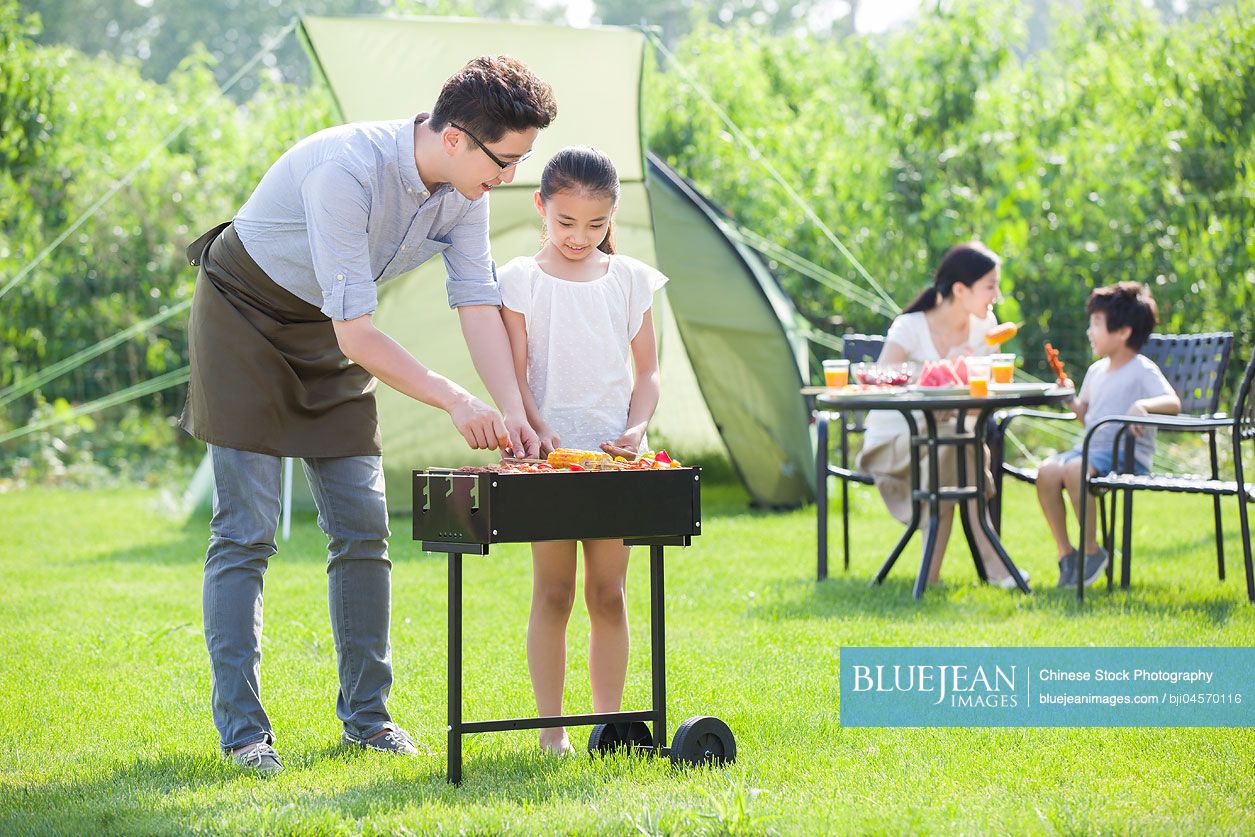 Young Chinese family barbecuing outdoors