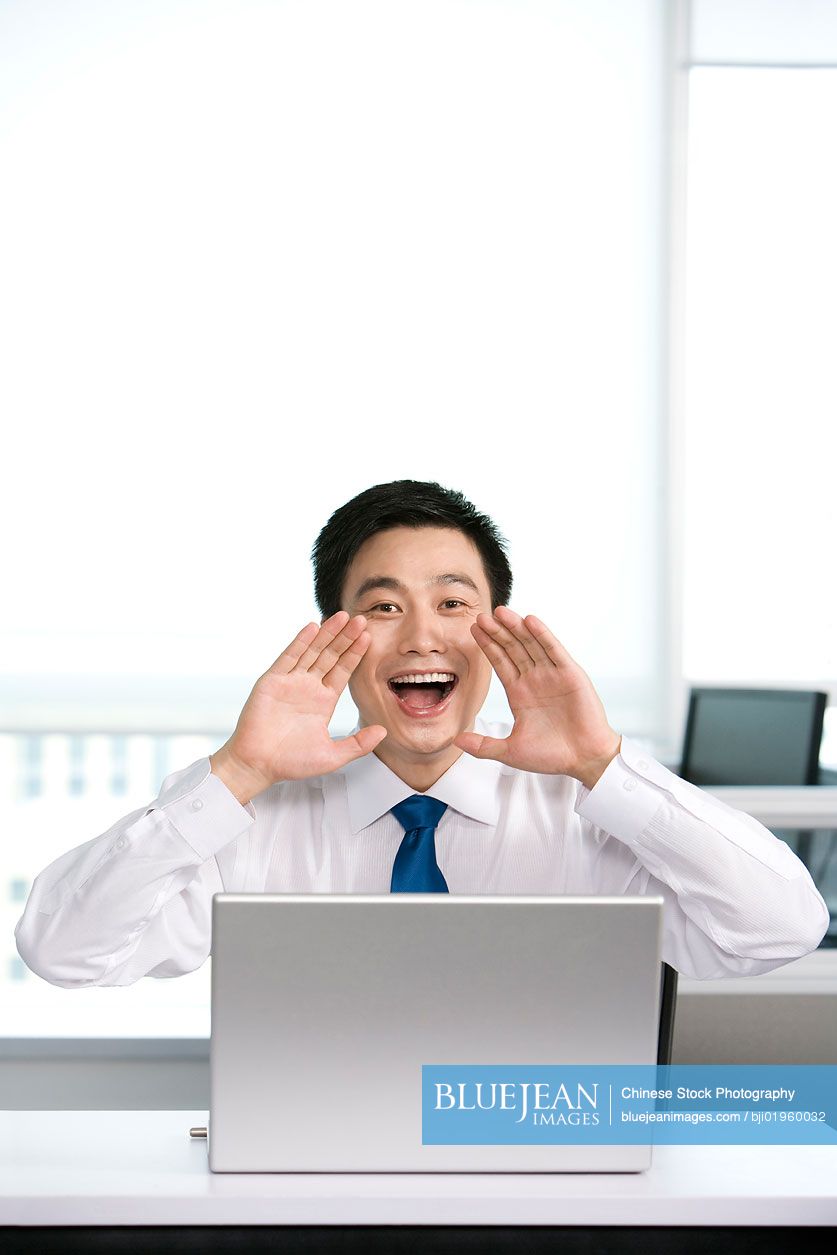 Happy Chinese office worker at his desk