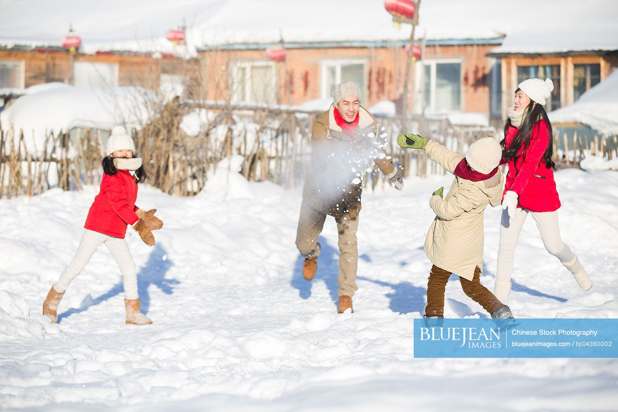 Young Chinese family having a snowball fight in the snow