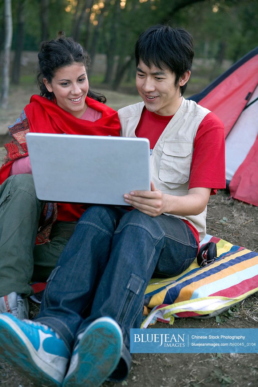 Young Chinese Couple Camping With Computer
