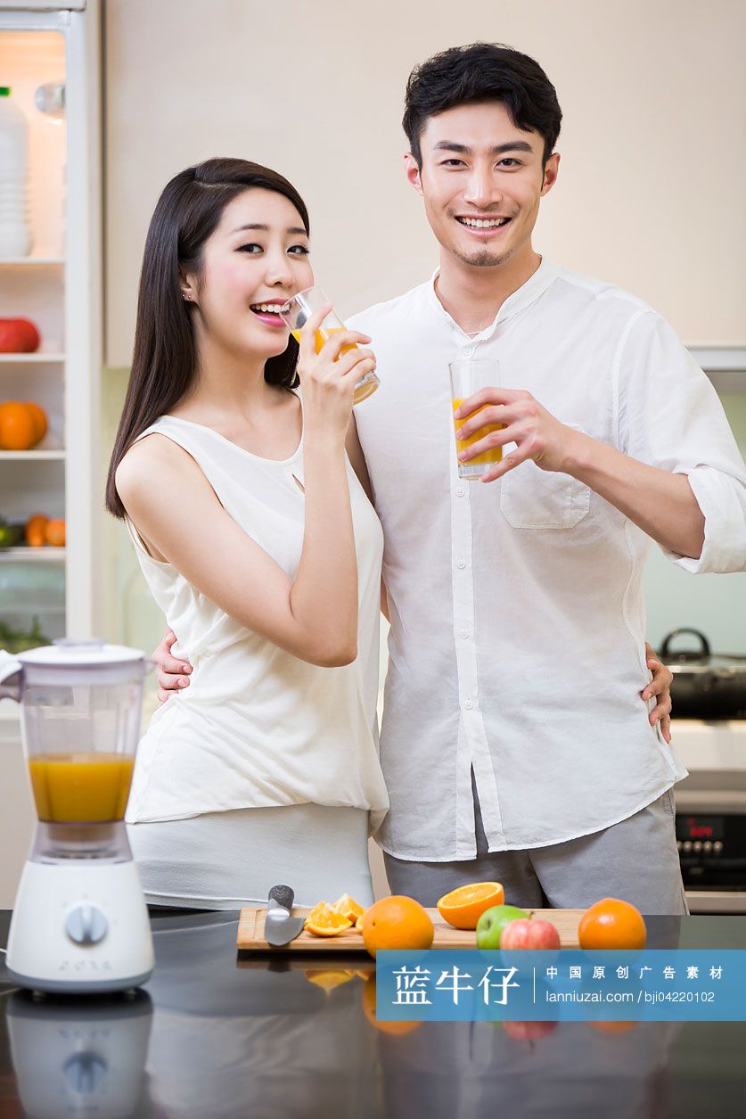在厨房里喝橙汁的年轻夫妇