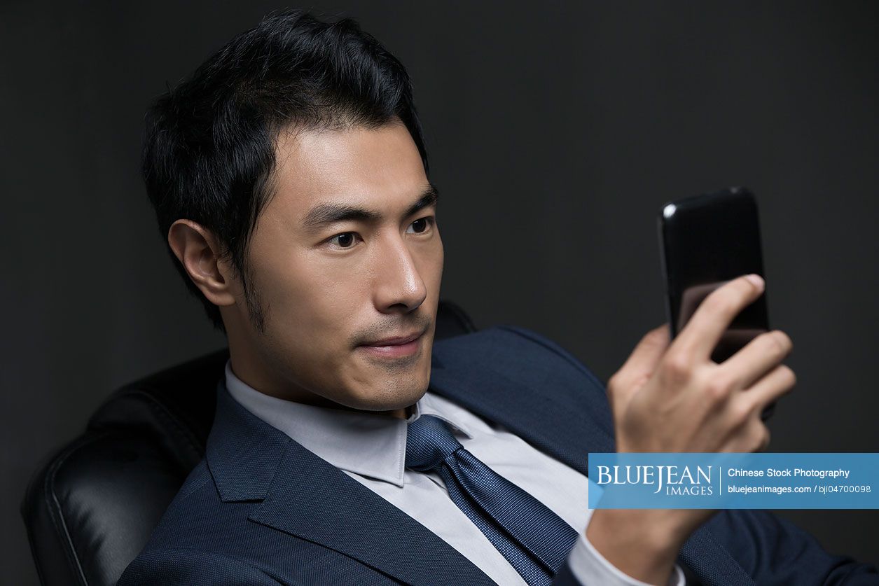 Confident Chinese businessman using smart phone