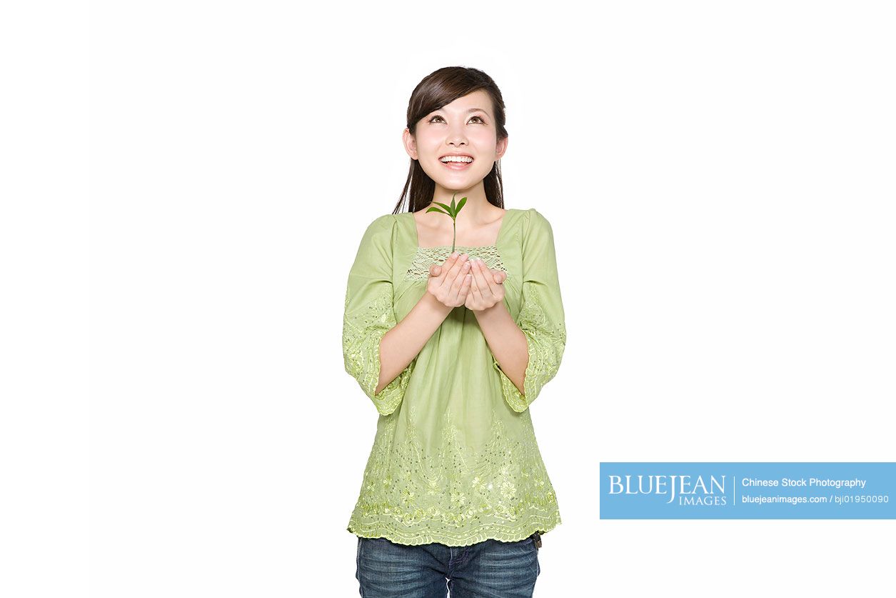 Portrait of young Chinese woman holding seedling
