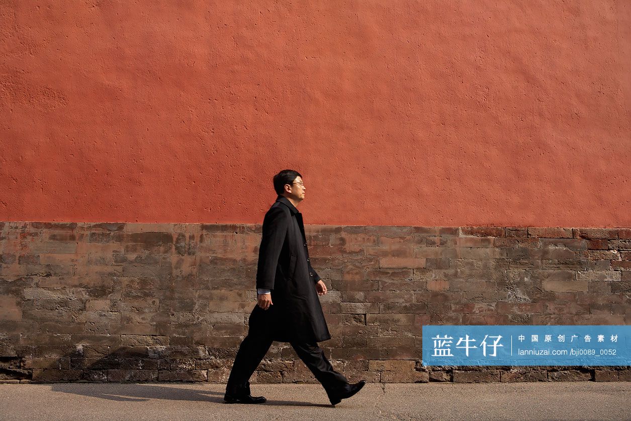 商务男士在宫墙下行走