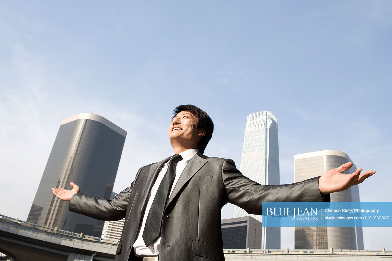 Chinese businessman with arms outstretched, urban scene