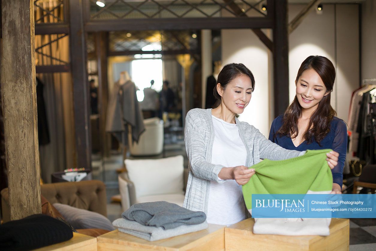 Chinese clothing store owner helping customer with choosing Chinese clothing